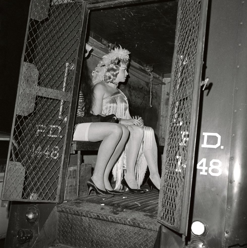 Monochrome, two drag queens sitting inside of a police truck