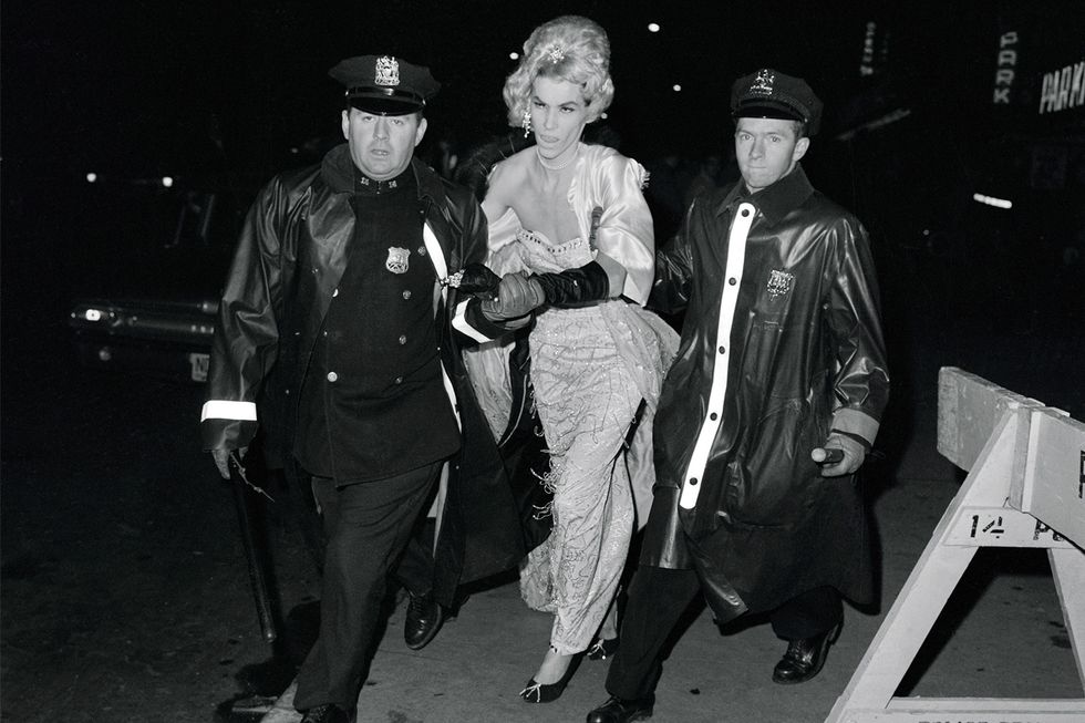 Monochrome, drag queen in the middle of two police officers, grabbed by force.